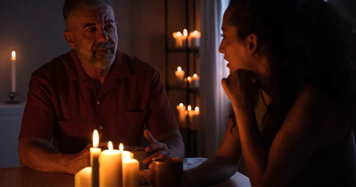 Two people talking by candlelight during a prolonged blackout at home