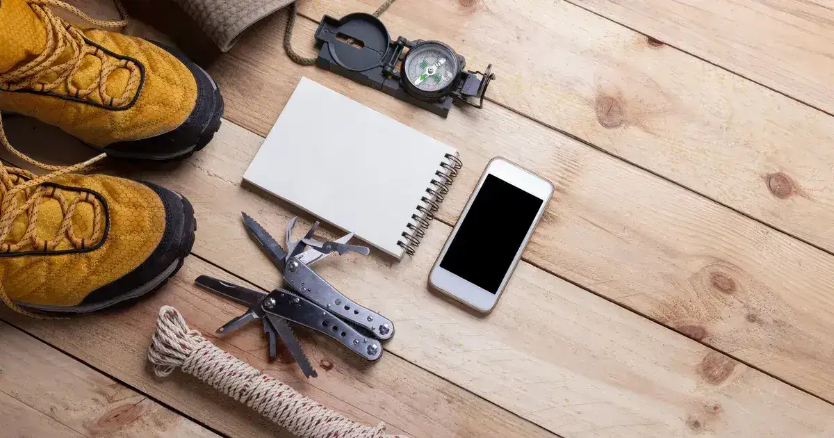 Survival gear and camping equipment organized on a flat surface including backpack, tools, and supplies for a 72-hour bag