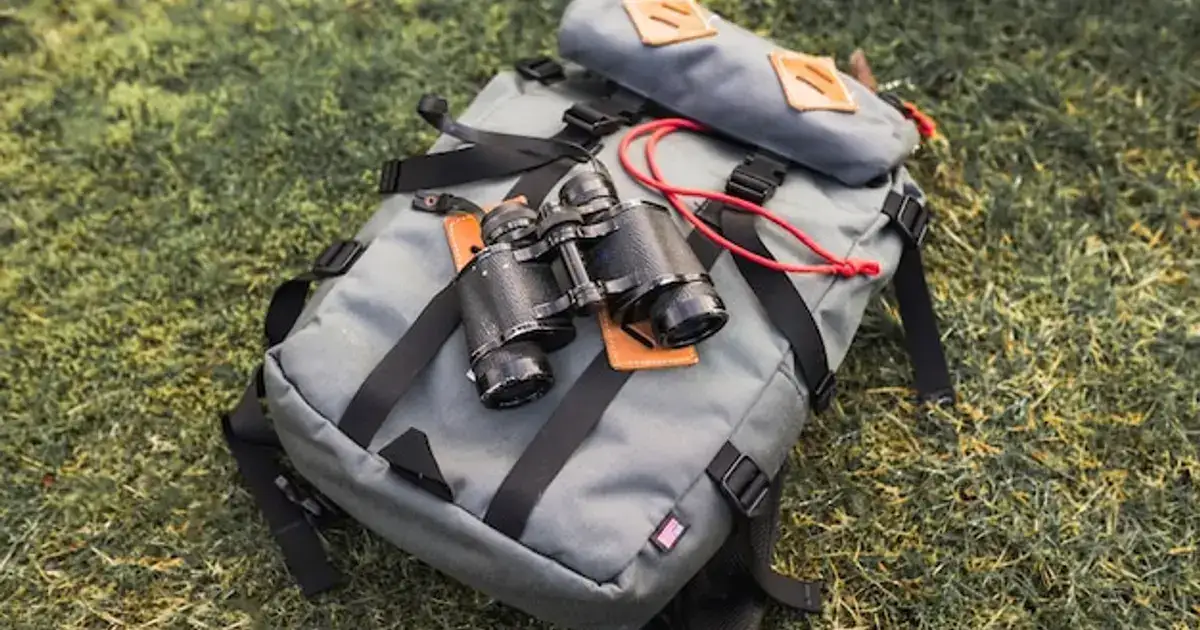 Survival backpack with emergency equipment outdoors on grass